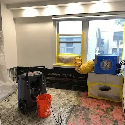 A dehumidifier and an air mover drying a room with the flooring removed, equipment brought to Poway water losses
