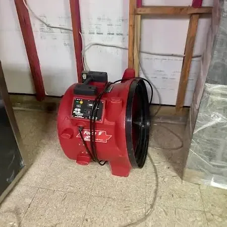 A red air mover drying a room with the lower wall opened and plastic hung, the usual Poway setup