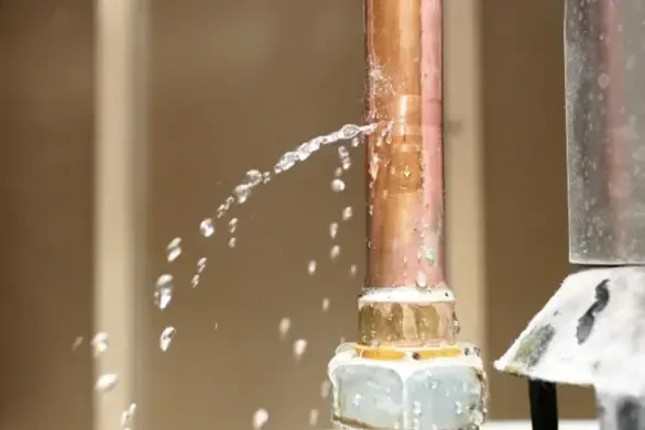 Water spraying from a split fitting on a copper supply pipe