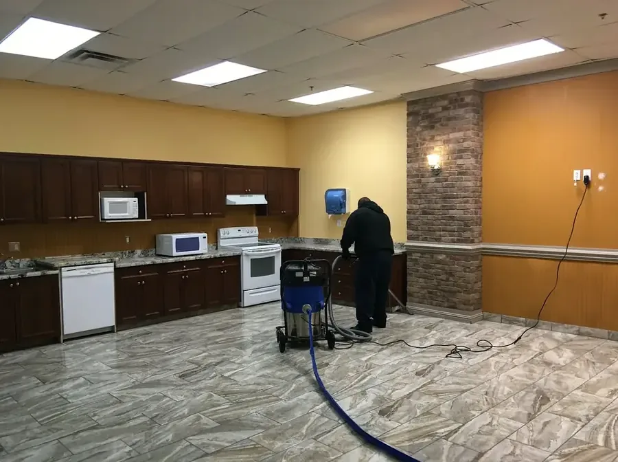 Restoration tech running an extraction wand across a soaked floor in a home
